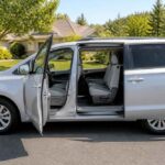 Srebrny minivan zaparkowany na ulicy z otwartymi drzwiami bocznymi i widocznymi siedzeniami
