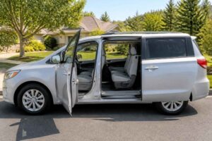 Srebrny minivan zaparkowany na ulicy z otwartymi drzwiami bocznymi i widocznymi siedzeniami